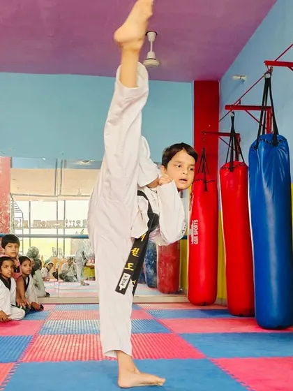 A demonstration of pure flexibility and technique. This student is executing a perfect vertical high kick, a fundamental skill in Taekwondo that requires immense practice and control.