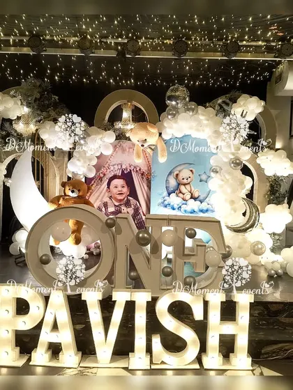 A dreamy "Twinkle Twinkle Little Star" themed first birthday stage, featuring a moon prop, teddy bears sitting on clouds, and a soft, ethereal color palette.