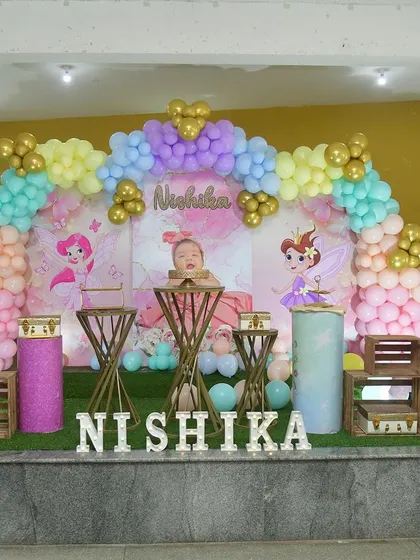 The full view of the Annaprashan ceremony decor, with a pastel balloon arch and a custom photo backdrop.