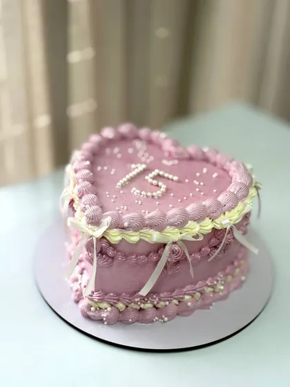 A heart-shaped vintage cake for a 15th birthday, with delicate piping and ribbon details.