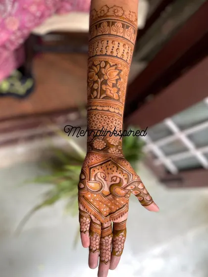 This full arm bridal mehndi features elegant swan motifs on the hand. The design extends up the arm with bands of floral and traditional Indian patterns.