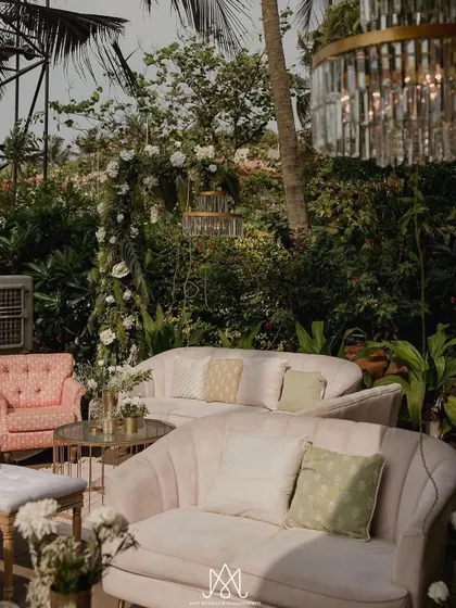 Another view of the pastel pink lounge seating, with a crystal chandelier hanging above, blending luxury with the natural outdoor setting.