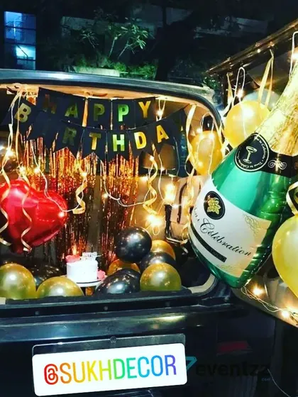 Take the celebration anywhere with our custom car boot decorations. This surprise birthday setup includes a "Happy Birthday" banner, a shimmering backdrop, and a large champagne bottle foil balloon, turning the car into a personal party space.