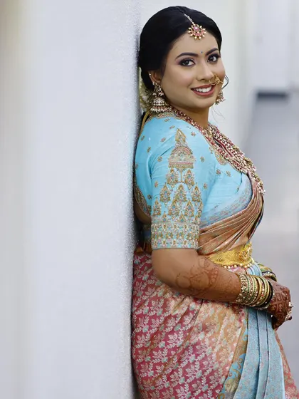 Our beautiful client Nidhi radiates timeless charm in our custom temple-design blouse. The sky-blue blouse features intricate gold embroidery inspired by temple architecture, crafted exclusively for her special event.