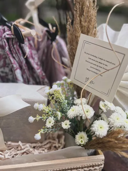 The personal note is always central. Here, it's placed thoughtfully amidst the florals and styled gifts.