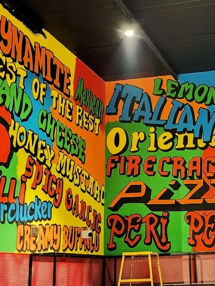 A corner view of the menu mural, showcasing the different food items and flavors in a playful, overlapping graffiti style.