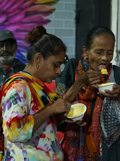 Two women share a meal near our Annam Brahma service van. We believe that when we share, we truly care.