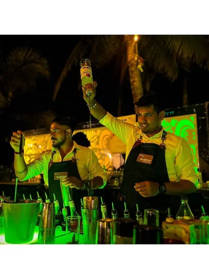 Our bartenders working in sync under vibrant green lighting. We create an atmosphere that's both cool and professional, ensuring the bar is a highlight of your event.