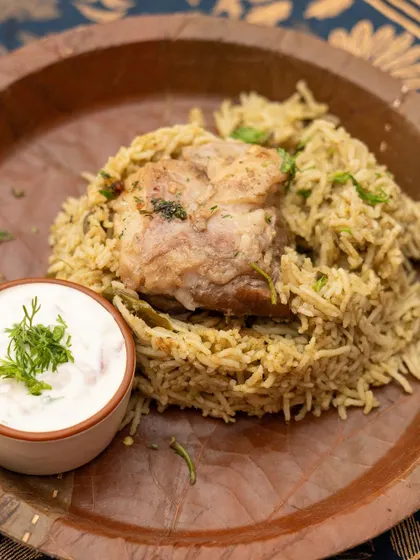A beautiful serving of my Mutton Palav, garnished and ready to be enjoyed with a side of fresh raita. The dish is presented on a rustic plate, highlighting its earthy origins.