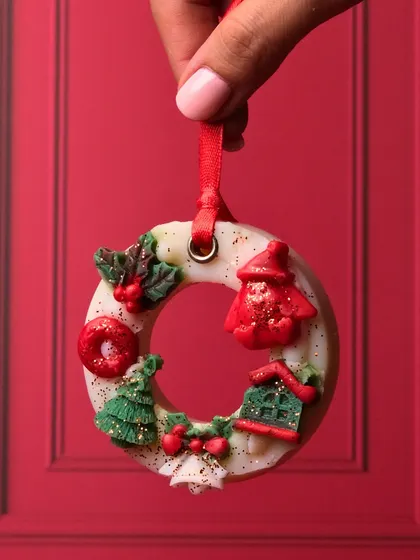 A close-up of my Christmas wreath wax sachet. You can see the tiny, handcrafted details like the Santa hat, house, and trees that make this piece so special.