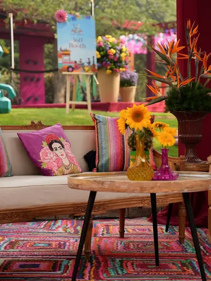 A close-up of a lounge area, with a Frida Kahlo cushion on a plush sofa and a large, sculptural rabbit in the background. The decor is a playful mix of art, color, and whimsy.