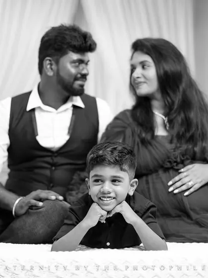 A creative composition in black and white, with the son smiling in the foreground while his parents share a loving glance behind him. This layered portrait tells a story of both individual personality and family connection.