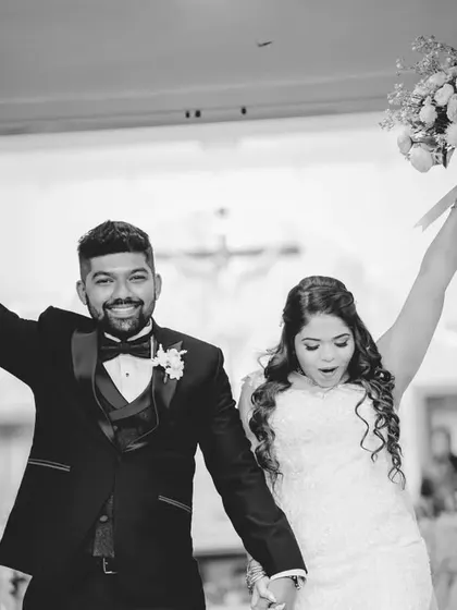 A triumphant and joyful black and white photo of the couple exiting the church. Their raised arms and happy faces tell a story of celebration.