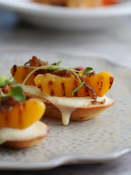 Delicate tartlets topped with grilled peaches and a creamy base. A sweet and savory bite.