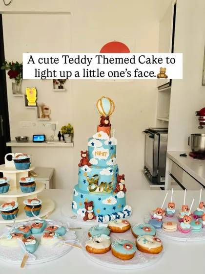 A beautiful dessert table setup featuring a four-tier teddy bear cake, matching cupcakes, donuts, and cakesicles.
