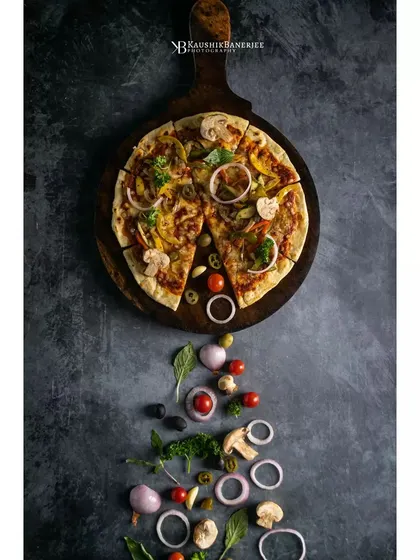 A rustic vegetable pizza, styled with its fresh ingredients cascading down the frame. This creative flatlay for Double Tree by Hilton tells the story of the pizza from ingredients to finished product.