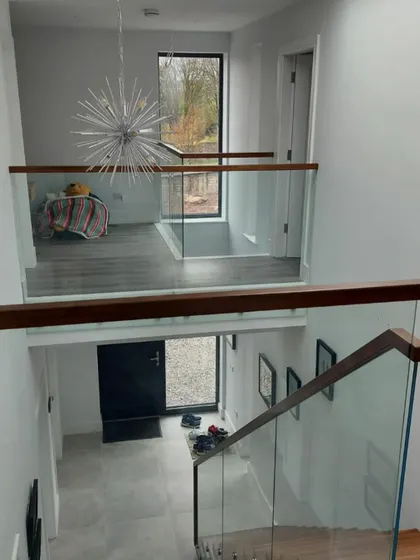 A look down into the entryway from the mezzanine landing. The glass balustrade provides safety without creating a visual barrier.