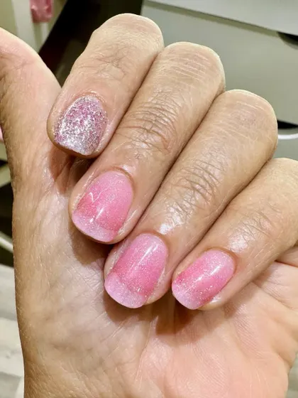 A subtle and sweet look on natural nails. This client opted for a sheer pink shimmer polish with one full silver glitter accent nail for a touch of fun.