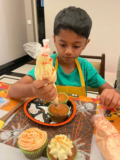 The concentration is real. This young baker is mastering the art of piping frosting onto his Halloween-themed cupcakes, all made from scratch.