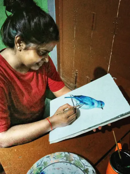 A candid photo of me painting the watercolor bluebird. This is a moment of quiet happiness, lost in the process of creating art.