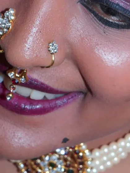 A macro shot highlighting the intricate nose and lip jewelry, showcasing the fine details of the traditional costume.