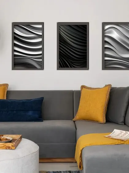 A comfortable grey sectional sofa is styled with bold yellow and blue cushions. Above, a triptych of abstract black and white art adds a sophisticated, graphic element to this modern and minimal TV room.