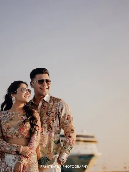 The couple smiles, looking out towards their future, with the cruise ship softly blurred in the background.