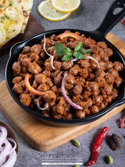 A hearty bowl of Pindi Chana. The lighting is focused to bring out the rich, dark color of the gravy and the texture of the chickpeas.