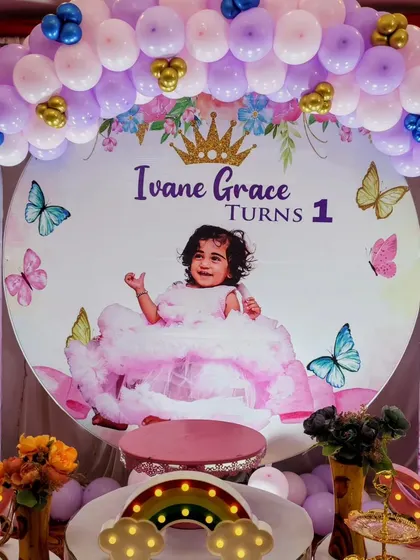 A beautiful butterfly-themed backdrop for Ivane Grace's first birthday, with a photo of the birthday girl.