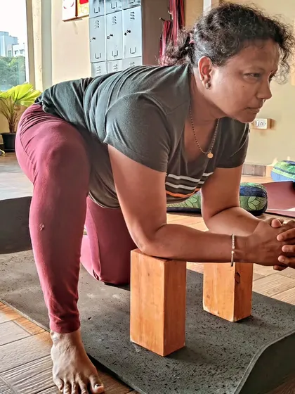 A student practices Lizard Pose using blocks for support. The morning light in our studio creates a calm and focused atmosphere for practice.