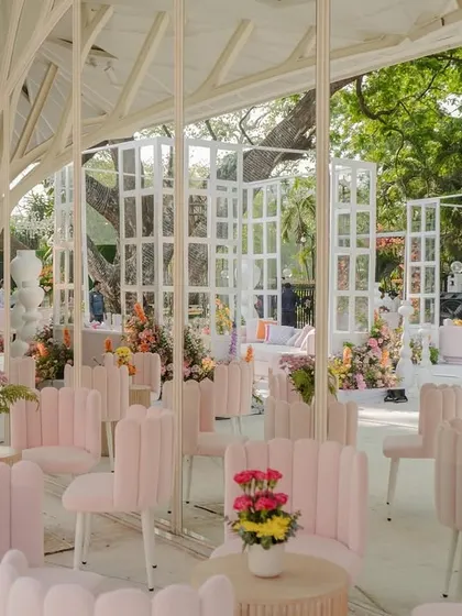 Modern and whimsical seating for the "Bloom" wedding. The unique, shell-backed pink chairs are arranged in a beautiful glasshouse-like structure, creating a light and airy lounge space for guests.