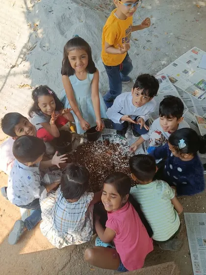 A happy group of children gathers around their finished soil-mixing project. The smiles on their faces show the pride and joy they take in their work.