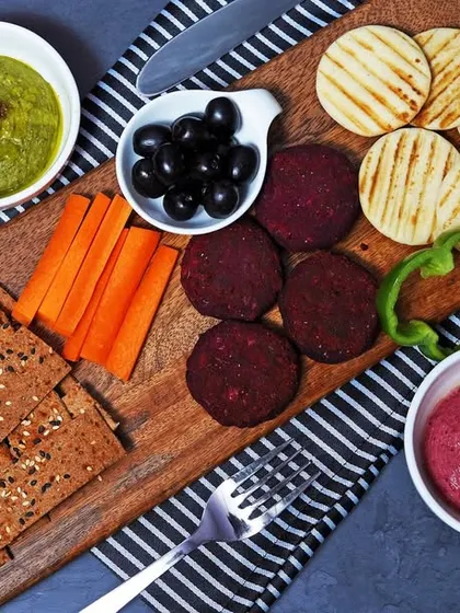 A healthy and appetizing grazing board with various types of hummus, crackers, and fresh vegetables. This demonstrates my ability to shoot savory and health-focused food platters for cafes and catering businesses.