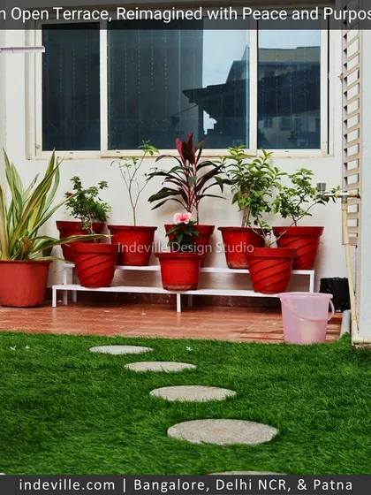 A small section of a terrace I reimagined with purpose. A simple patch of artificial grass with stone steppers is complemented by a stand of vibrant red potted plants, adding a pop of color.