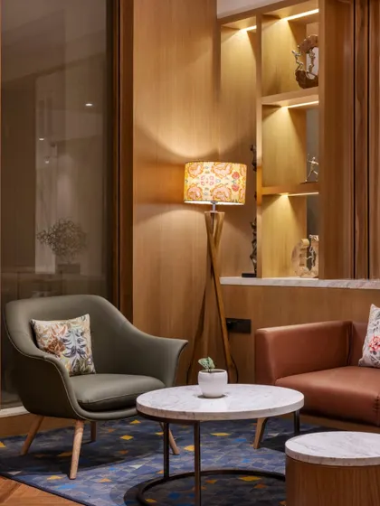 A comfortable seating nook in the lobby designed for guests to relax. The material palette includes warm wood paneling, soft leather upholstery, and a marble-topped coffee table, creating a cozy and refined corner.