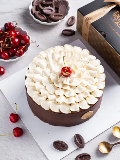 Our modern take on the Black Forest cake, topped with a cloud of vanilla namelaka and a single fresh cherry. This entremet is a complex assembly of chocolate, cherry, and cream, perfect for a refined palate.