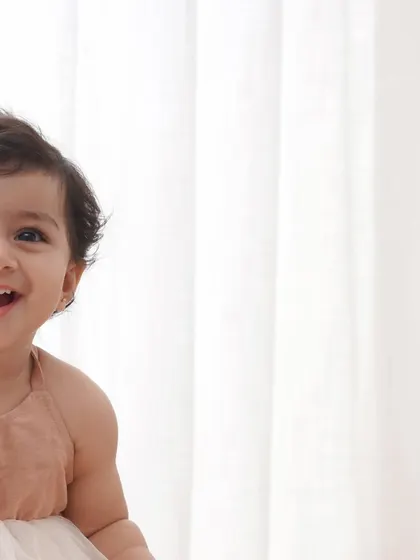 A joyful, laughing baby girl captured in a candid moment during her first birthday photoshoot.