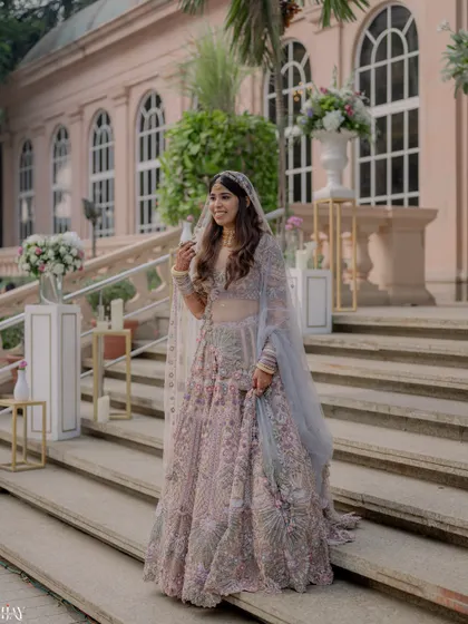 The bride descending a grand staircase, her pastel lehenga looking ethereal and elegant.