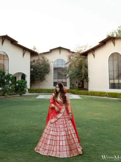 A wide shot of the bride, Dolly, in the manicured lawns of the venue. This portrait captures her grace and the beauty of the wedding location.