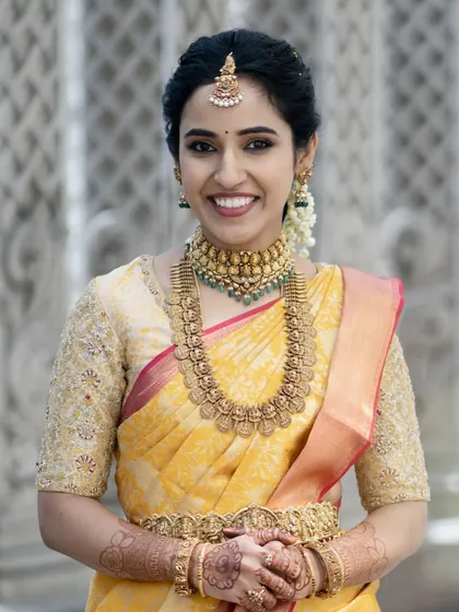 A close-up portrait of a bride on her wedding day. The makeup is soft and natural, with a beautiful smile that lights up her entire face.