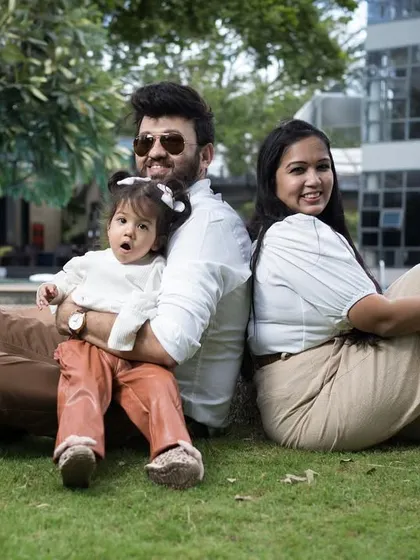 A relaxed family portrait on the lawn. The family sits back-to-back, creating a casual and connected image that feels natural and comfortable.
