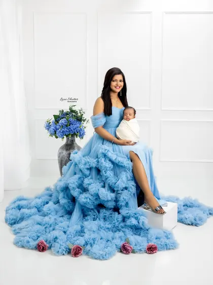 A full-length view of the mother in her stunning blue ruffled gown, creating a beautiful and artistic maternity-style portrait with her newborn.