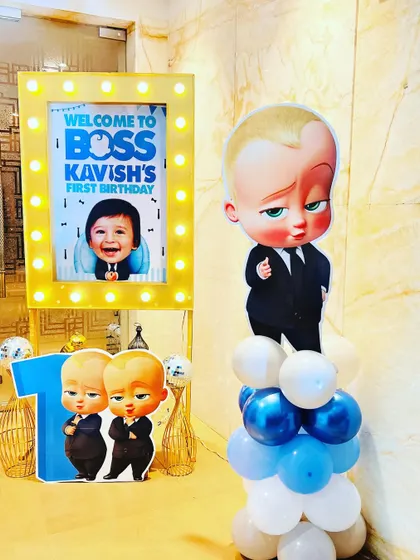 A fun entrance setup for a "Boss Baby" themed first birthday, with a personalized light-up poster and character cutouts.