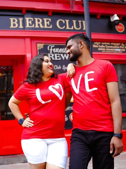 Another great shot of the couple in their matching "LOVE" t-shirts, this time in front of a vibrant red building that makes the photo pop.
