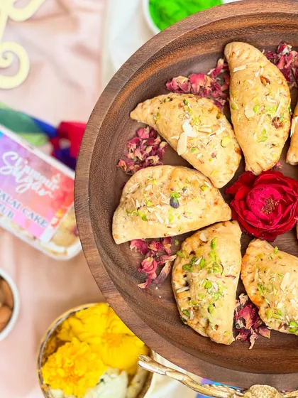 A platter of our baked Mava Gujia, sprinkled with pistachios and rose petals, part of our special Holi menu.