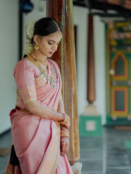 Our bride in a beautiful pink silk saree, taking a moment before the main ceremony. The traditional jasmine braid and temple jewelry complete her classic South Indian bridal look.