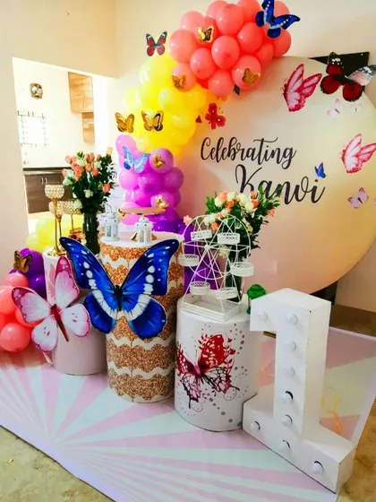 A vibrant butterfly-themed first birthday with bold colors. The mix of blue, pink, and yellow creates a very energetic and joyful atmosphere.
