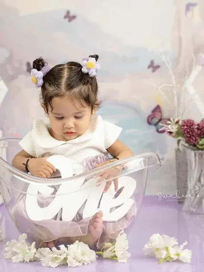 Holding the "one" sign in her tub, this little girl is celebrating her first birthday in a unique and adorable way.