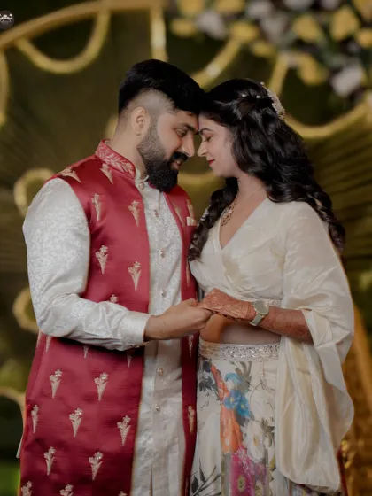 An intimate portrait of a couple touching foreheads, holding hands, and sharing a quiet moment amidst the wedding celebrations. The focus is on their connection and elegant wedding attire.