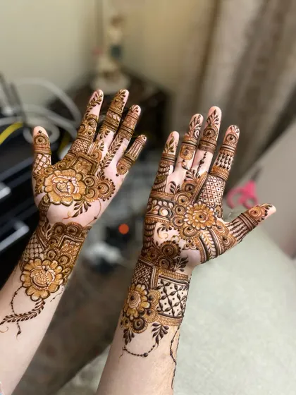 Two hands displaying complementary intricate henna designs, perfect for a festive occasion.